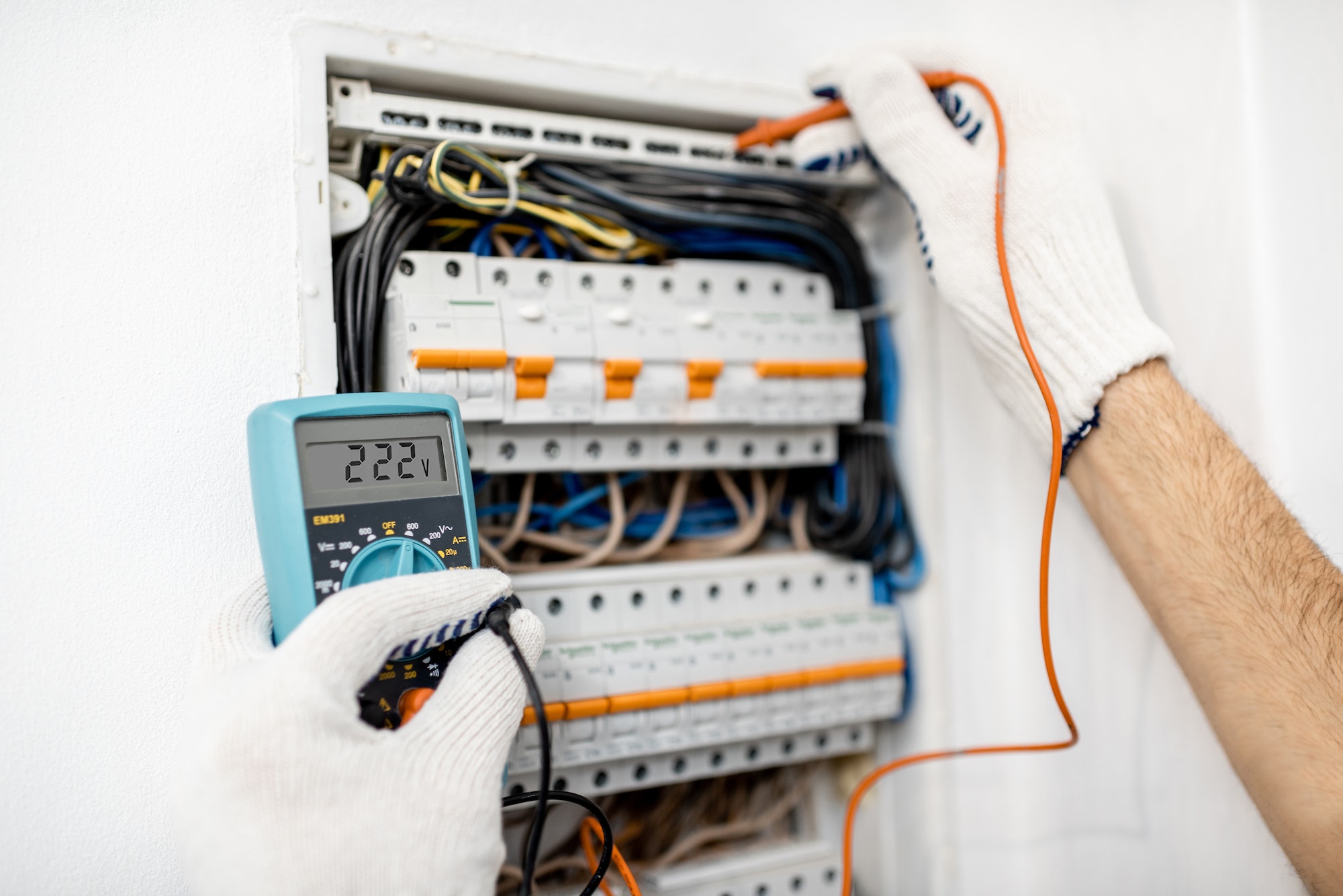 Elettricista misura tensione quadro elettrico con multimetro.
