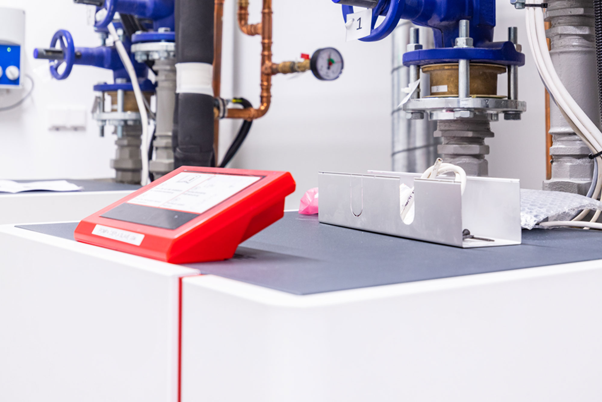Pannello di controllo rosso vicino a tubature industriali.