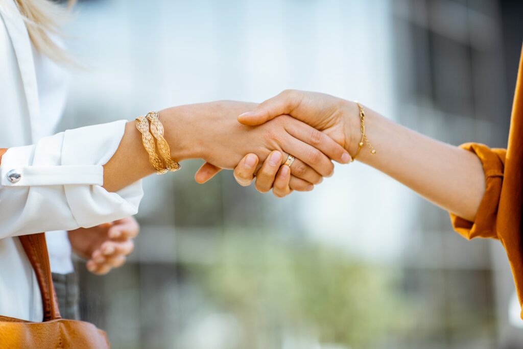 Due persone si stringono la mano con braccialetti.