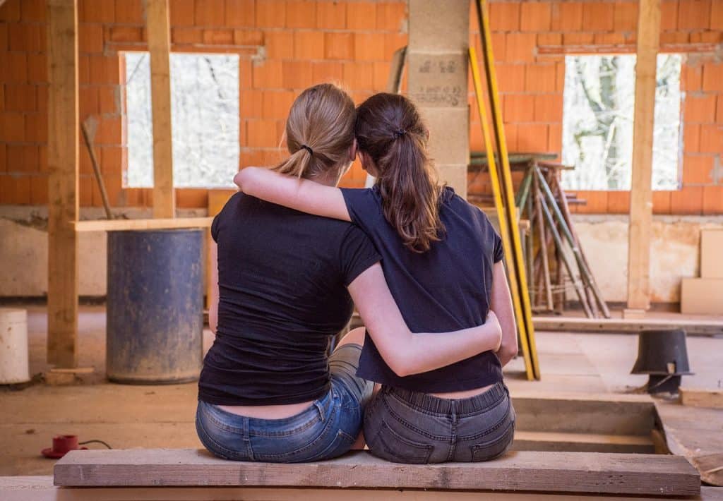 Due persone sedute abbracciate in un cantiere.