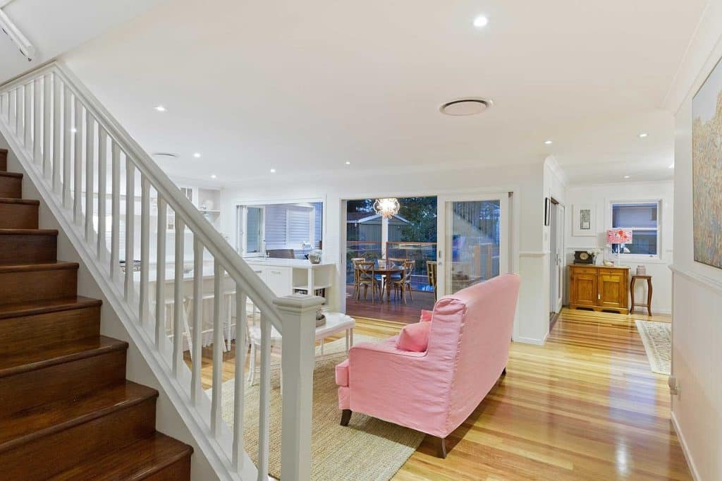 Interno di casa moderna con scala e divano rosa.